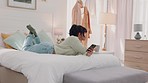 Woman, drinking coffee and phone of a young person from India lying on a home bedroom bed. Female using mobile technology online looking at internet, web and social media app content in a house