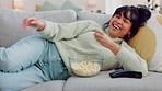 Popcorn eating, watching tv and woman on living room sofa with comedy movie, relax with comic film and happy with subscription service on the couch. Girl with food and funny television show in house