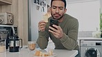 Asian man, phone or eating breakfast food with morning coffee in house or home kitchen. Confused person on communication mobile technology for social media, events app or internet health meal recipes