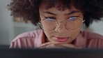 A black woman with glasses, watching film on a laptop at home and using hands to hold her head. 5g technology, the internet and streaming services allow people to view online content media worldwide 