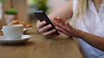 Woman, hands and phone browsing social media, scrolling and zoom on wooden table at cafe. Closeup of female hand on smartphone, browse feed or checking news and searching internet at coffee shop