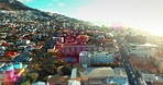 Lens flare, aerial drone view of urban city and suburb neighborhood in the summer sun. Mountain side house, apartment and buildings between street or avenues. A creative, calm and cinematic skyline  