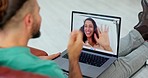 Couple on virtual video call with laptop screen and man on sofa at home, woman wave hello. Excited international people or friends on zoom call for international networking or online love connection