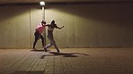 Hip hop, night and girl dance group on a city street dancing under a light in freedom performance, teamwork and action. Friends, dancers and creative women with urban, energy and artistic movement