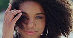 Face, hair and beauty with a black woman in the wind outdoor closeup with a happy or positive attitude. Haircare, natural and afro with an attractive young female standing outside during the day