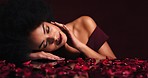 Sexy, seductive and black woman in petals from rose looking for love touching her face. Beauty, makeup and flowers, sensual lady from Brazil. Elegance, desire and flirt, Romance, red lips and roses.