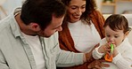 Family, baby and parents on a sofa bonding and playing with toy in a living room, happy, relax and cheerful together. Love, happy family and curious boy relaxing with loving mother and father at home