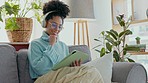 Headphones, graphic designer and woman on tablet drawing on home sofa. Tech, relax and creative female, freelancer or remote worker from Brazil streaming music, radio or audio podcast while working.