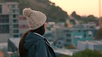 Fashion, view and city with a young woman looking out over an urban town during winter at sunset. Travel and rooftop with an attractive female enjoying the cityscape sightseeing and architecture