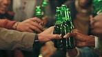 Friends, toast and cheers at outdoor party celebration at night with beer, bottle and alcohol. Happy people enjoy celebration, freedom or birthday with a drink at a social event in the evening