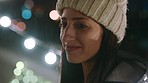 Face, rain and night with a woman outdoor in a beanie getting wet from cold weather in the city. Water, fashion and smile with a happy young female standing outside during winter in a dark urban town