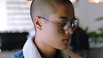 Young man with coffee while reading on his tablet in workplace cafeteria, during a break from work. Asian, gen z youth serious and checking news with trendy hipster piercing and glasses in closeup.