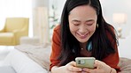 Social media, happy and asian woman on bed with phone smile, internet and relax in home. Meme, online and girl on 5g mobile smartphone texting, chatting and browsing web in house bedroom on weekend
