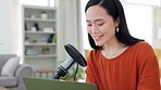 Podcast, microphone and live streaming with an asian woman presenter typing on a laptop while recording or broadcasting. Influencer, media and radio with a female streamer talking in her home studio