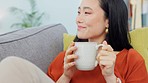 Coffee, thinking and woman on the sofa to relax with peace and calm in a house. Happy, Asian and young girl with a smile, idea and happiness with drink of tea on the couch during winter in a home