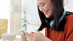 Smartphone, typing and happy woman social networking online, using phone mobile app or chat in her apartment. Asian gen z girl on cellphone communication, social media update or music subscription
