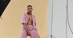 Fashion, photography and male model working at photo shoot for beauty, style and designer clothing. Modelling, pose and trendy black man in professional studio set with yellow backdrop and equipment