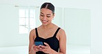 Happy, woman and phone in ballet studio texting, chatting or social media with smile for communication indoors. Female dancer smiling on a break with technology in conversation on mobile smartphone