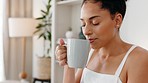 Happy woman smelling the coffee aroma or scent while relaxing in the living room at her home. Happiness, relax and calm girl from Mexico drinking warm espresso, cappuccino or caffeine in the morning.