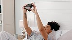 Camera, black woman and selfie in a bed with happy, smile and relax girl posing, playful and having fun in her home. Photography, photographer and woman taking pictures while lying in a bedroom alone