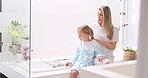 Morning, mother and daughter in bathroom with hair brush for grooming care routine in family home. Motherhood, child and mama brushing hair of young kid in house and getting ready for the day.