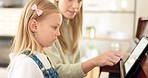 Girl, teacher and learning piano on tablet with music, reading notes and development in home. Woman or mother teaching daughter to play a musical instrument in lesson with digital technology in house