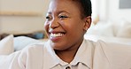 Happy, smile and black woman relaxing on a sofa while watching tv in the living room of her modern house. Happiness, laughing and African lady streaming a movie while sitting on a couch in her lounge