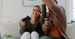 Fun, playing and love with a gamer couple laughing, joking or bonding while gaming on a sofa in the living room of their home together. Game, funny and laugh with a man and woman enjoying video games