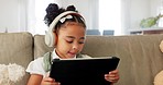 Tablet, headphones and child with e learning app, watch video on website for kids or online education on sofa at home. Girl listening to audio ebook, music or digital video games on living room couch