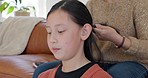 Asian child, home hair braid and mother on sofa for hair care, bonding and styling in living room. Mom couch, young daughter and hairdresser beauty with mama girl in family home for love in Japan