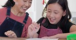 Homework, mother and child with smile for education, learning and writing on paper in a house. Happy, Asian and young girl thinking of the solution to a math problem with her mom at a table in a home