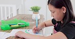 Art, education and drawing with a student girl doing homework or being creative at a table in her home. Study, learning and school with a female child pupil working in a coloring book in her house