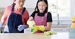 Parent, child and spray bottle to wipe kitchen surface, table or countertop in housekeeping education or healthcare learning. Talking asian mother, smile and happy girl in spring cleaning maintenance