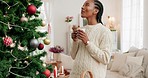 Black woman, coffee and Christmas with smile for tree decorations, holiday and relax at home. Happy African American female enjoying drink and smiling for December festive season with decor indoors