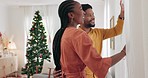Christmas, morning and love with a black couple in their home, opening the curtains in a living room to see the view. Window, happy and celebration with a man and woman in a house during the holidays