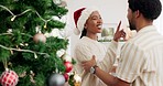 Couple, love and christmas in a living room with happy, smile and relax people embrace, flirt and laugh celebration. Black family, tree and festive party by black woman and man in their home together