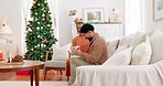 Christmas, black couple and gift with hug, being happy and smile for holidays, together or in lounge on sofa. Love, man or woman enjoy vacation, embrace or bonding for loving on couch in living room 