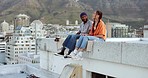 Friends, couple couple hanging out and sitting rooftop talking with view of cityscape on summer evening. Diversity, friendship and freedom, urban dating for trendy woman and black man relax on date.