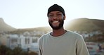 Face, happy and street style with a black man outdoor in the city with nature in the background during summer. Portrait, fashion and urban with a handsome young male standing outside in a bright town
