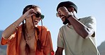 Friendship, flirting and couple with sunglasses in city sitting on building rooftop laughing. Love, friends and romance, urban dating and freedom for gen z woman and man with smile on crazy fun date.