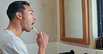 Man with toothbrush in bathroom mirror for dental health, wellness or oral hygiene or care. Young asian male cleaning teeth in the morning with brush in his home for beauty, healthy and healthcare