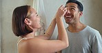 Happy, skincare and couple doing a self care routine together in the bathroom of apartment. Happiness, love and woman helping man with cosmetic eye pads for with love, care and a smile in their home.