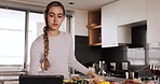 Cooking, video and woman with a tablet in the kitchen for dinner, lunch or breakfast food in a house. Young chef with a recipe on technology with vegetables for nutrition, salad diet and health