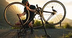 Bicycle, wheel and tyre on road with man athlete fix problem on rim outdoor in sunset. Cyclist, bike or broken in street on training, fitness and exercise ride for sport or prepare for competition