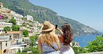 Two women on holiday together taking photos of an Italian city using a smartphone