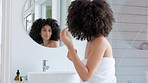 Black woman, natural hair and beauty while getting ready in bathroom mirror with hair care, growth shampoo and afro care at home. Happy african model during morning self care routine for wellness