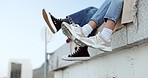 Shoes, legs and couple on rooftop in the city sitting together, have fun and bonding. Fashion sneakers, style and friends kick feet on building edge, enjoy weekend, freedom and holiday in urban town