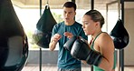 Coach, woman and punching bag while training, workout and talking in gym for health, wellness and fitness. Male trainer, female athlete and boxer practice, have conversation, for exercise and routine