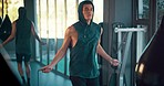 Fitness, health and man skipping rope in gym, motivation and mission for building strength with cardio exercise. Workout, sports training and strong athlete with jump rope and reflection in mirror.