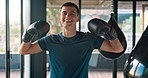 Young man, boxer and training with smile, for match and show arms in gym to prepare for competition. Male athlete, boxing and punch for fitness, health and workout with gloves, happy and practice.